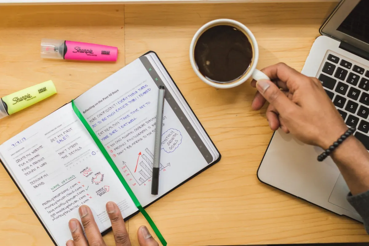 Flat lay of a business owner's desk with notebook, coffee and laptop