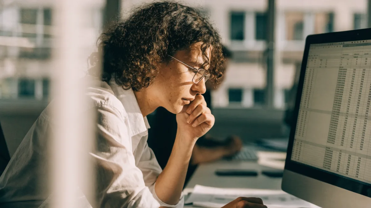 Accounts team member reviewing a spreadsheet of invoices on a monitor