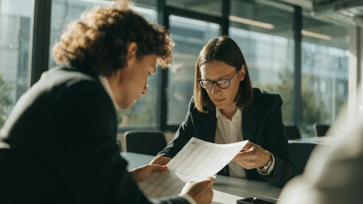 Two business professionals comparing financial documents at a table