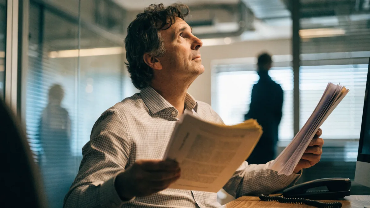 Business owner weighing up two sets of documents at a desk