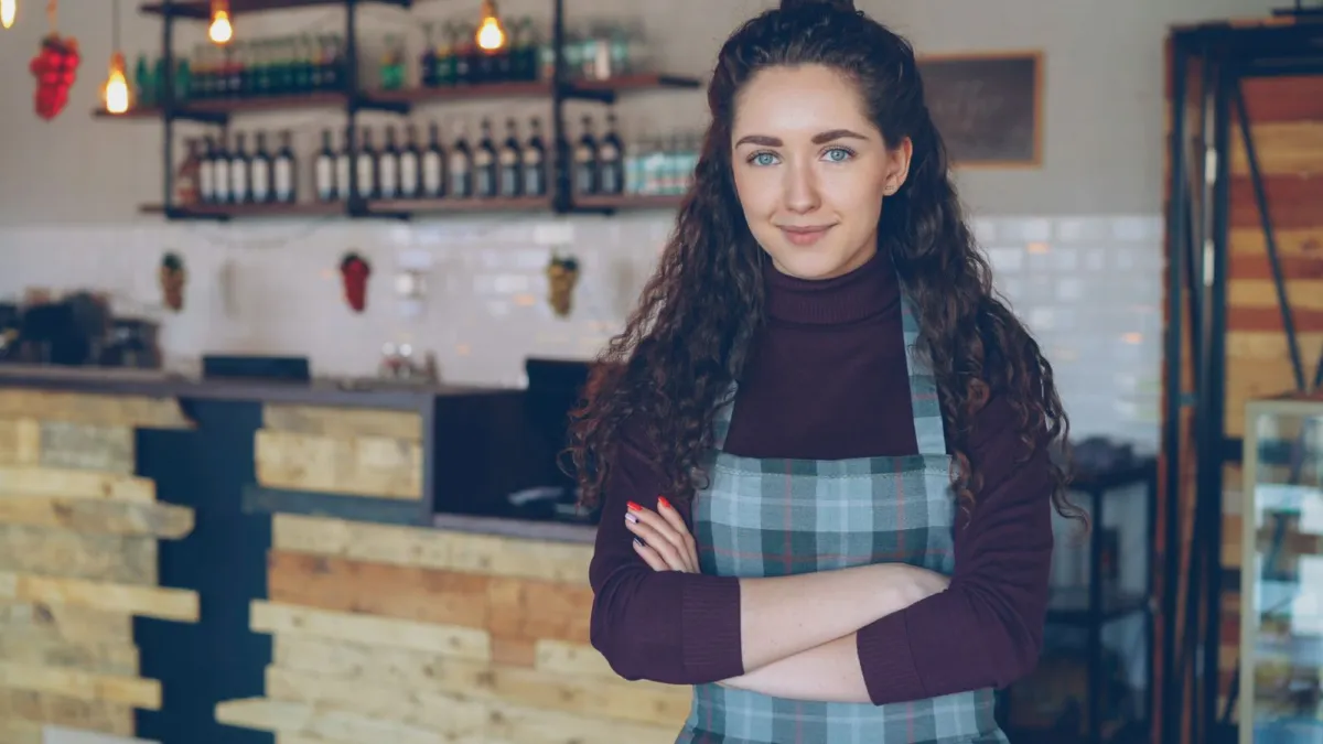 Café owner in an apron standing in front of her counter