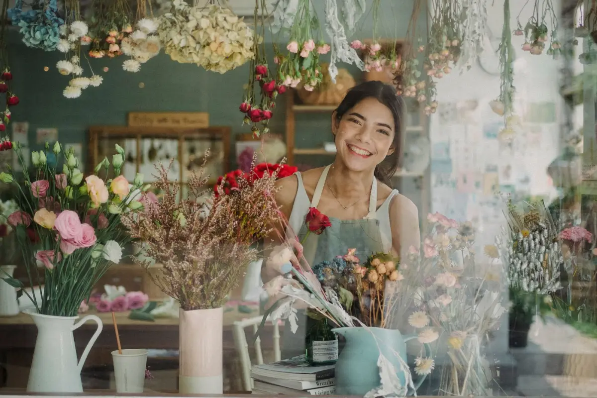 Florist smiling behind the window of her flower shop
